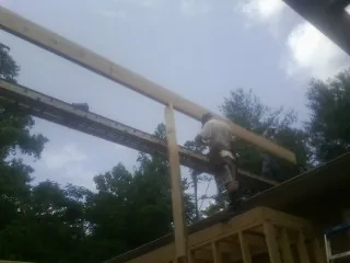 Carpenter setting a ridge beam over a new addition frame — Ice Dam Removal by Roofing Brothers in Minford