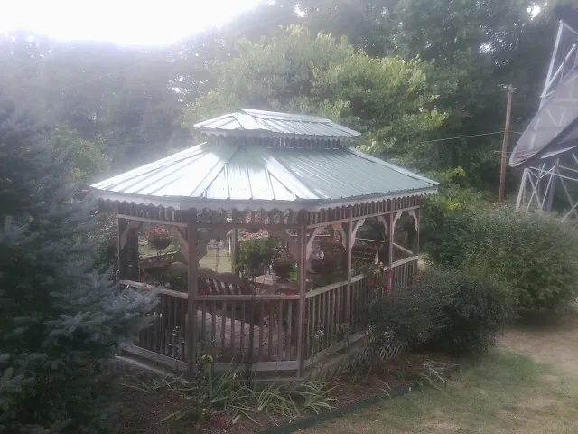 Green metal roof on a backyard gazebo surrounded by garden beds in Minford