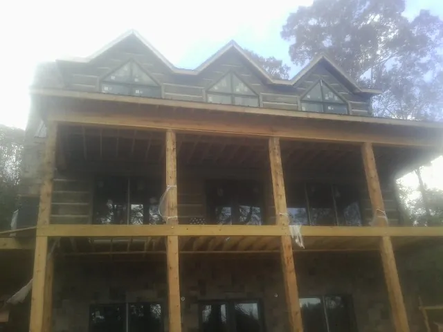 Dormers and porch framing on a large log home under construction — Roof Coating work by our crew in Minford