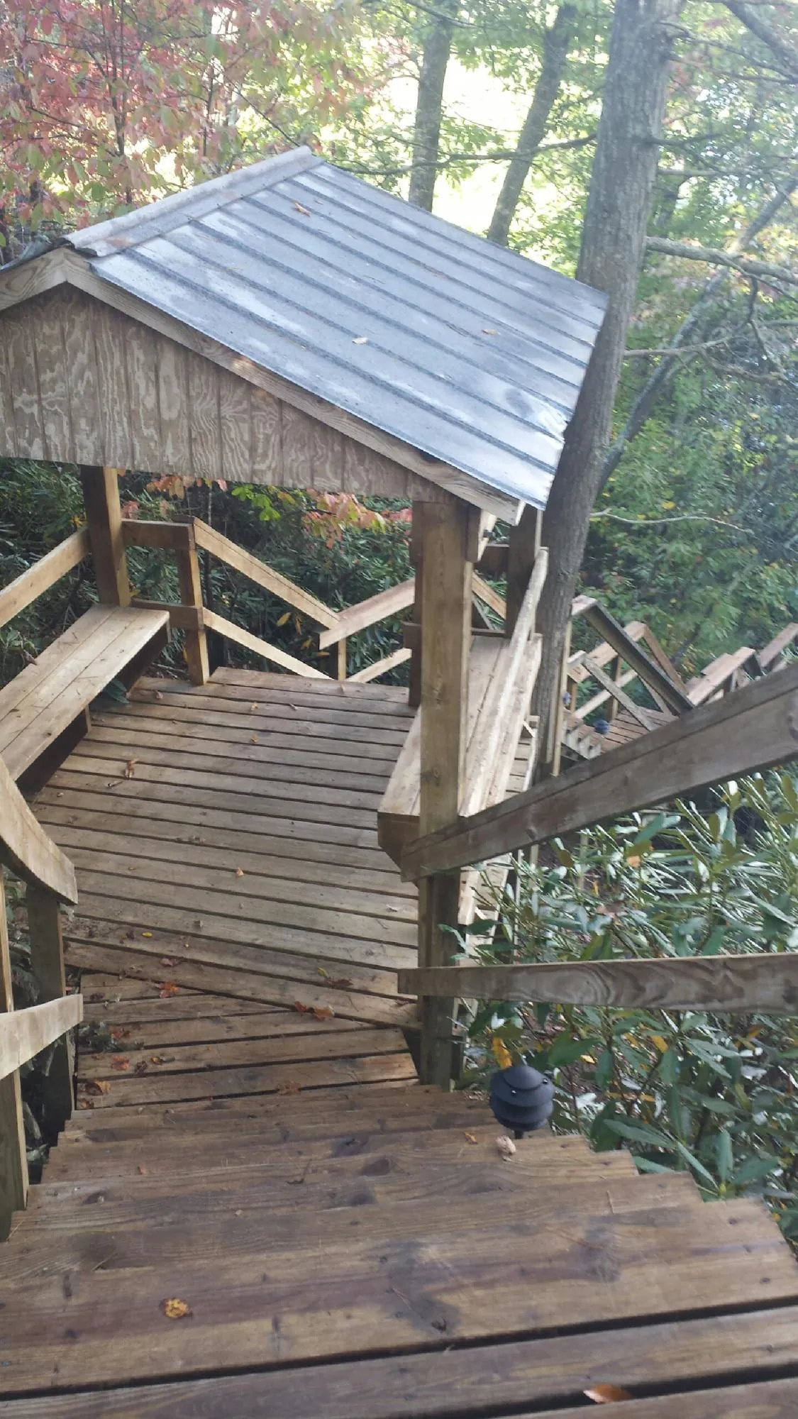 Metal roofed shelter over wooden steps on a wooded walkway — Skylight Repair & Installation work by our crew in Minford