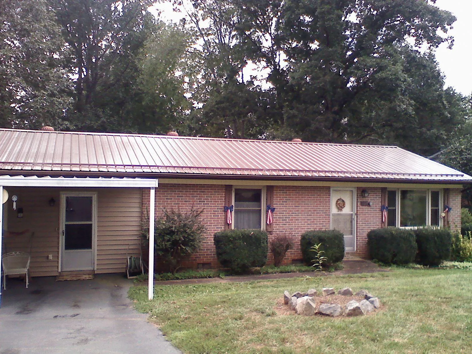 Bronze metal roof and carport on a brick ranch home — Roof Repair work by our crew in Minford