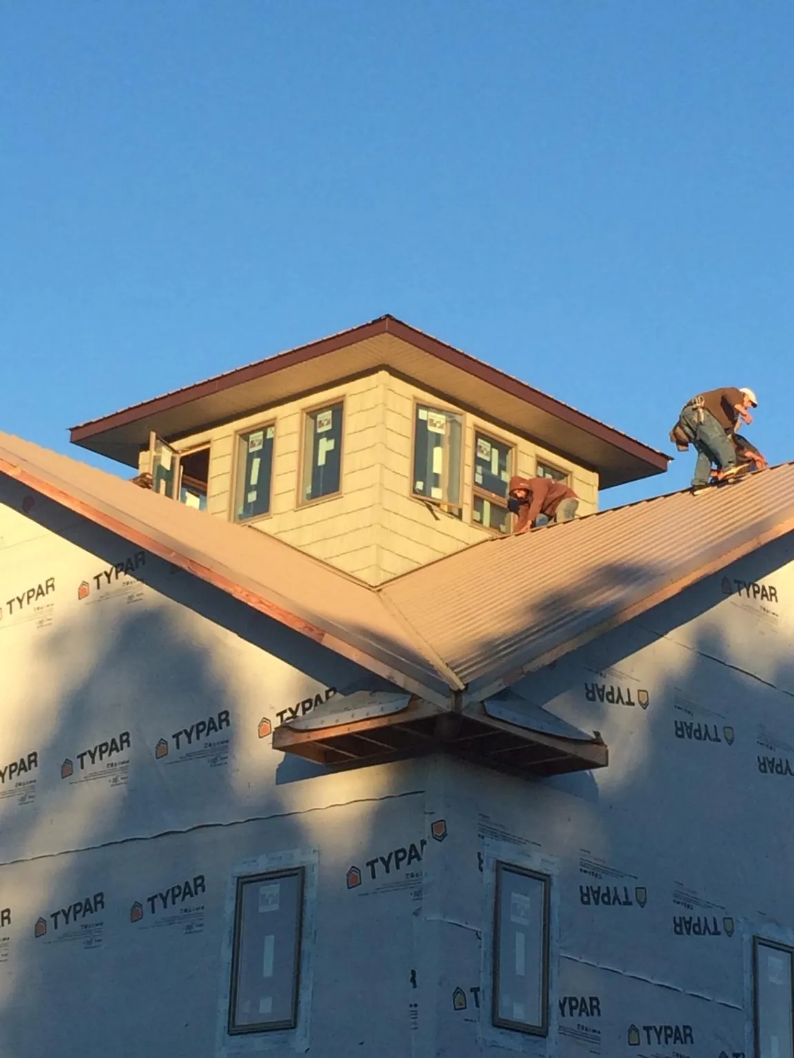 Roofers working around a rooftop cupola on a new metal roof at sunset — Roof Waterproofing in Minford by Roofing Brothers
